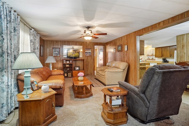 living room featuring light carpet, wooden walls, and ceiling fan