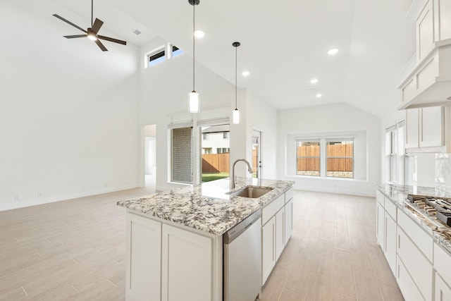 kitchen with sink, white cabinetry, stainless steel appliances, an island with sink, and decorative light fixtures