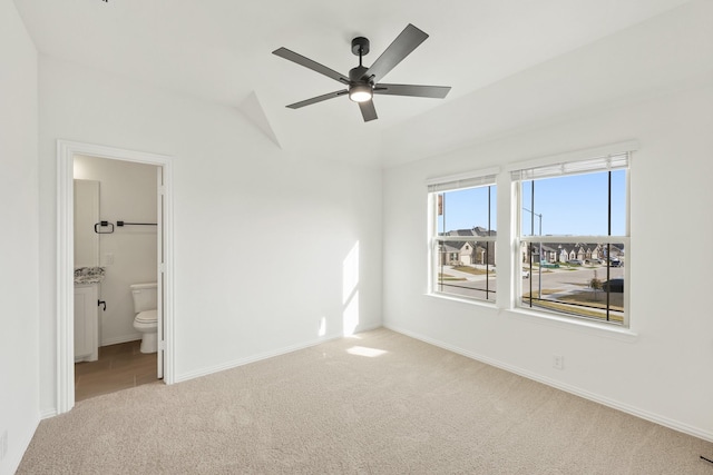 unfurnished bedroom with light colored carpet, ensuite bath, ceiling fan, and lofted ceiling