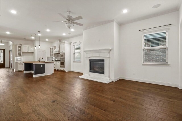 unfurnished living room with dark hardwood / wood-style floors, ornamental molding, sink, and ceiling fan