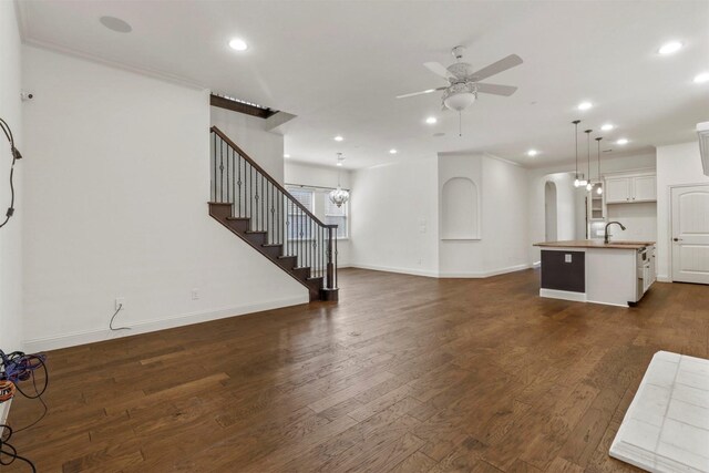 unfurnished living room with dark hardwood / wood-style floors, crown molding, sink, and ceiling fan