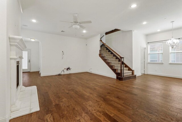 unfurnished living room featuring ceiling fan with notable chandelier and dark hardwood / wood-style flooring