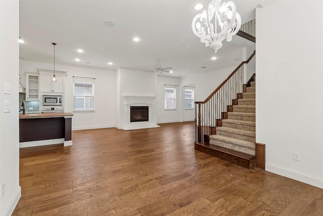 8604 Grassland Dr, Mckinney, TX 75070 - unfurnished living room with dark wood finished floors, recessed lighting, ceiling fan with notable chandelier, and a wealth of natural light