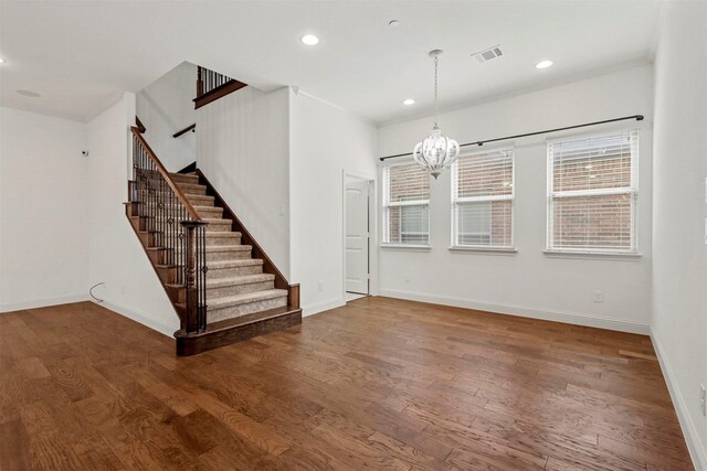 unfurnished living room with wood-type flooring and a chandelier