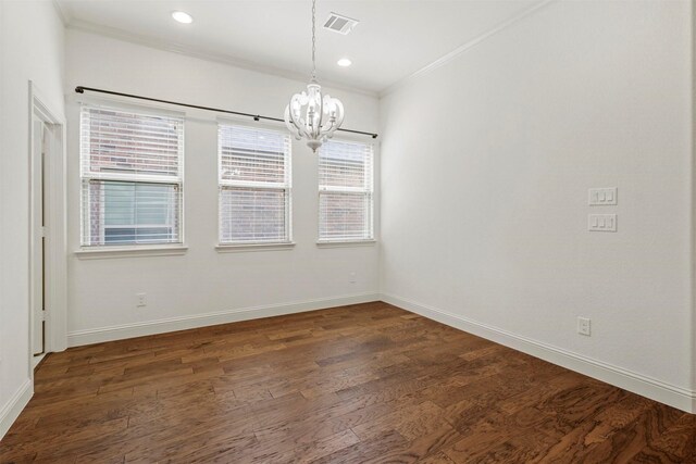 spare room featuring dark hardwood / wood-style floors, a notable chandelier, and ornamental molding