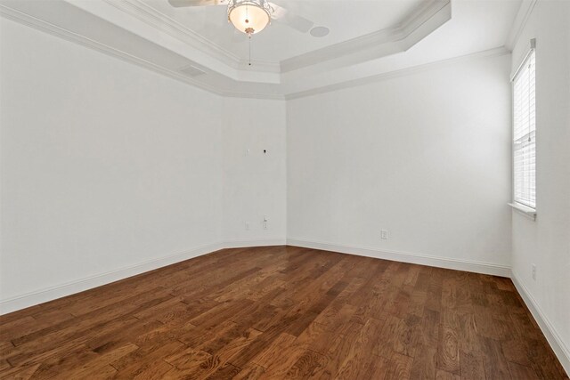 unfurnished room featuring hardwood / wood-style flooring, ornamental molding, ceiling fan, and a raised ceiling