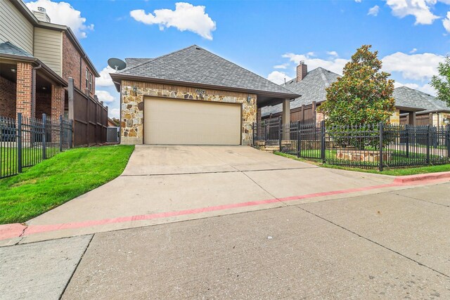 view of front of house with central AC unit, a garage, and a front lawn