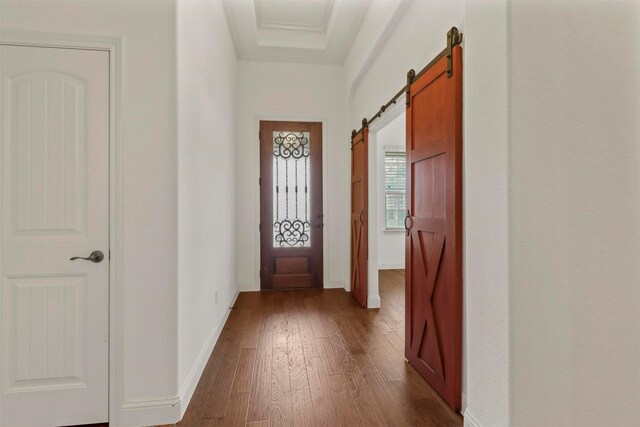 hallway with ornamental molding, dark hardwood / wood-style flooring, and a barn door