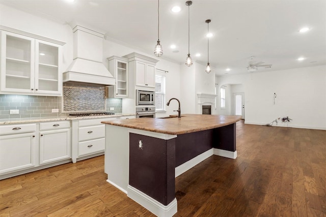 8604 Grassland Dr, Mckinney, TX 75070 - kitchen with a ceiling fan, a center island with sink, premium range hood, decorative backsplash, and appliances with stainless steel finishes