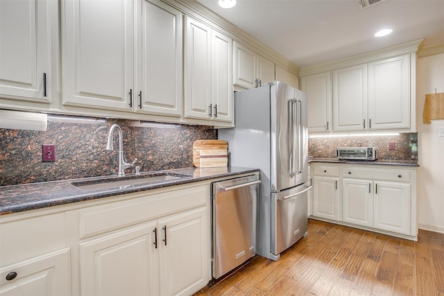 kitchen with appliances with stainless steel finishes, light hardwood / wood-style flooring, and backsplash