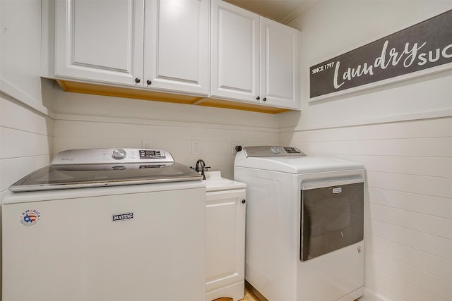 clothes washing area featuring cabinet space and separate washer and dryer