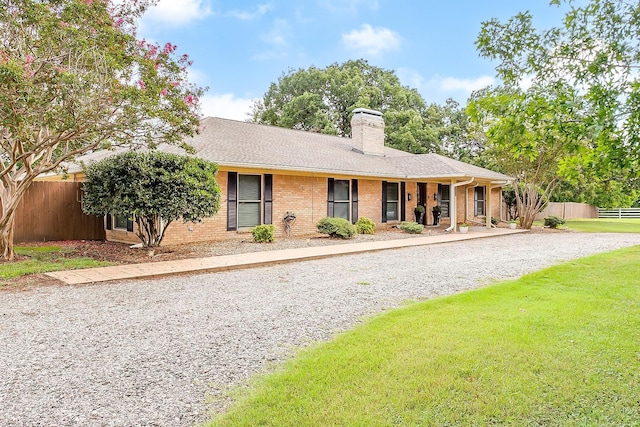 ranch-style house with brick siding, a shingled roof, fence, a front lawn, and a chimney