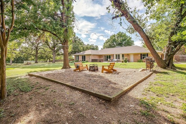 rear view of house with fence, a fire pit, a lawn, and brick siding