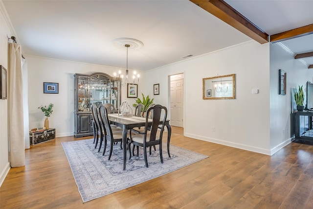 dining space with an inviting chandelier, crown molding, hardwood / wood-style floors, and beam ceiling