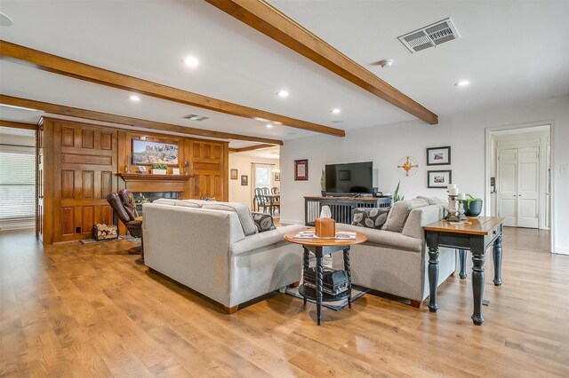 living room featuring beamed ceiling and light hardwood / wood-style flooring