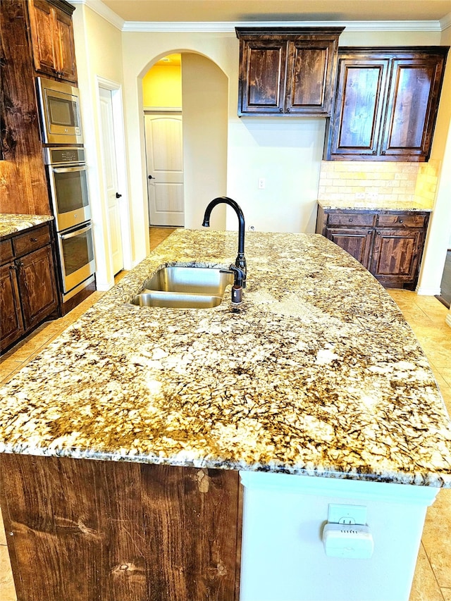 kitchen with appliances with stainless steel finishes, sink, light tile patterned floors, crown molding, and light stone countertops