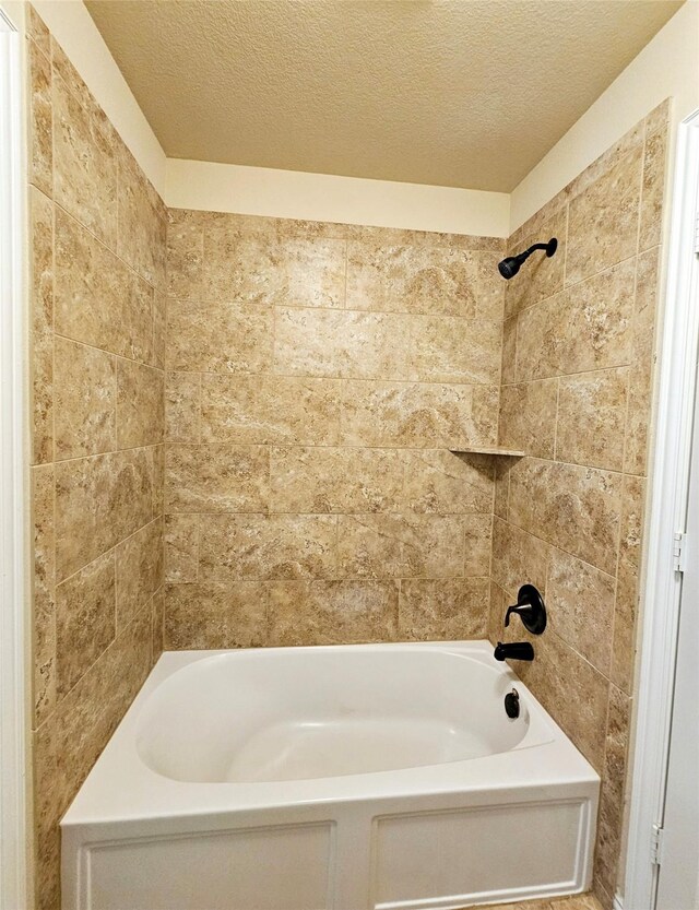 bathroom featuring tiled shower / bath and a textured ceiling