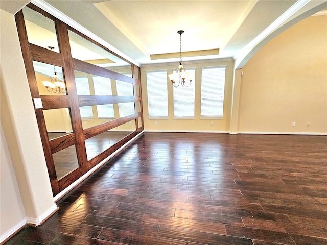 unfurnished room with dark wood-type flooring, a healthy amount of sunlight, a chandelier, and a tray ceiling