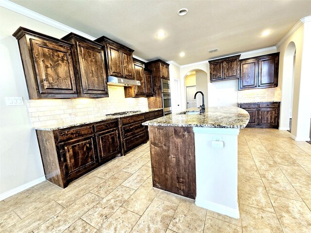 kitchen featuring appliances with stainless steel finishes, tasteful backsplash, ornamental molding, and an island with sink