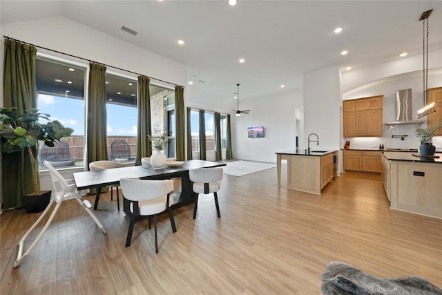 dining area with lofted ceiling, sink, light wood-type flooring, and ceiling fan