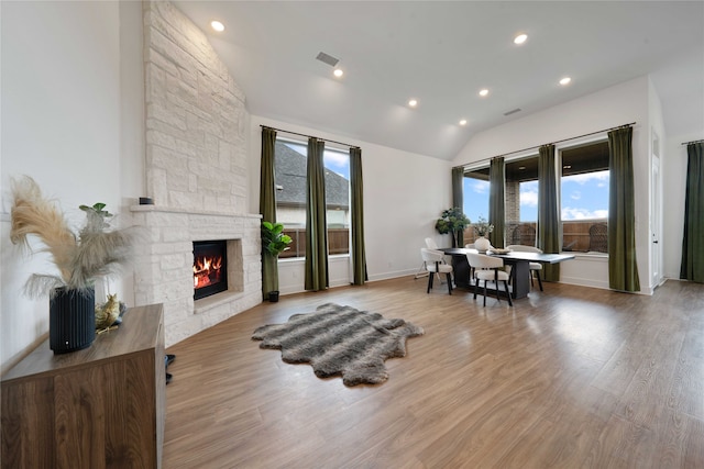 living room with a fireplace, wood-type flooring, and vaulted ceiling