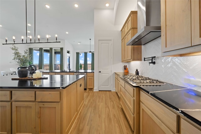 kitchen with decorative backsplash, light wood-type flooring, wall chimney exhaust hood, a kitchen island, and appliances with stainless steel finishes