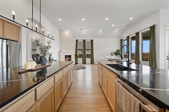 kitchen with light hardwood / wood-style flooring, stainless steel fridge, sink, a fireplace, and lofted ceiling