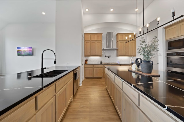 kitchen with light hardwood / wood-style flooring, stainless steel appliances, sink, hanging light fixtures, and wall chimney exhaust hood