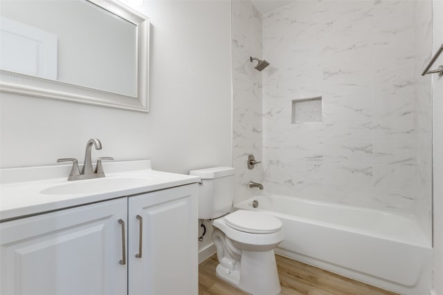 full bathroom featuring hardwood / wood-style flooring, tiled shower / bath combo, toilet, and vanity