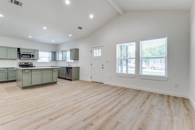 kitchen with a kitchen island, beamed ceiling, light hardwood / wood-style floors, green cabinetry, and appliances with stainless steel finishes