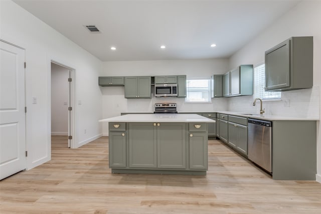 kitchen with light wood-type flooring, backsplash, a kitchen island, stainless steel appliances, and sink