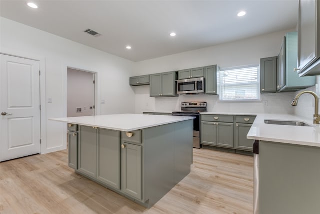 kitchen featuring stainless steel appliances, light hardwood / wood-style floors, a center island, and sink