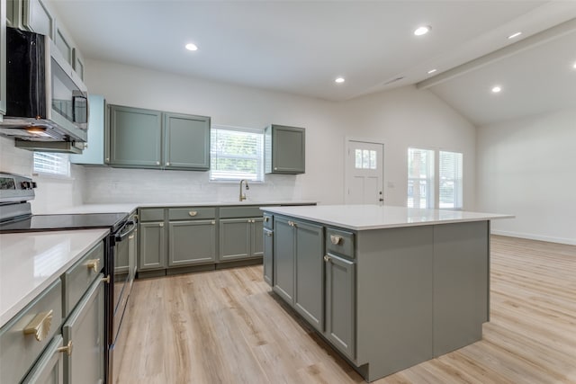 kitchen with lofted ceiling with beams, a kitchen island, appliances with stainless steel finishes, light hardwood / wood-style flooring, and backsplash