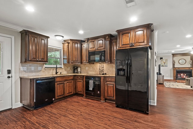 kitchen featuring dark wood-type flooring, black appliances, decorative backsplash, sink, and ornamental molding