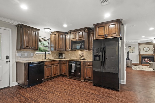 kitchen with dark wood-type flooring, sink, decorative backsplash, and black appliances