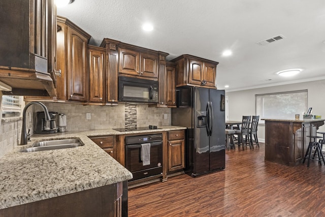 kitchen with sink, dark hardwood / wood-style flooring, decorative backsplash, dark brown cabinetry, and black appliances