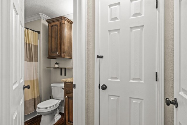 bathroom with vanity, hardwood / wood-style flooring, crown molding, toilet, and a textured ceiling