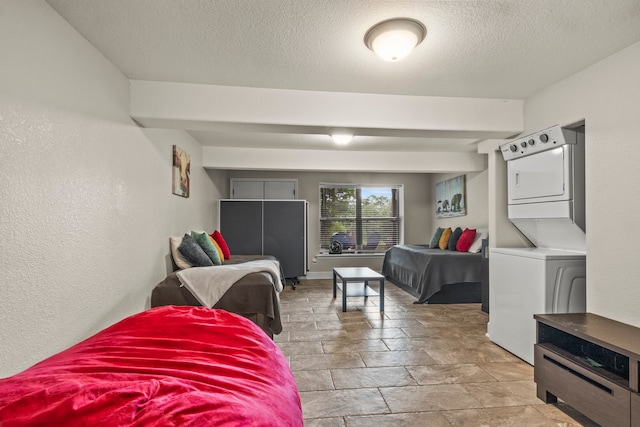 bedroom featuring stacked washing maching and dryer, a textured ceiling, and light tile patterned floors