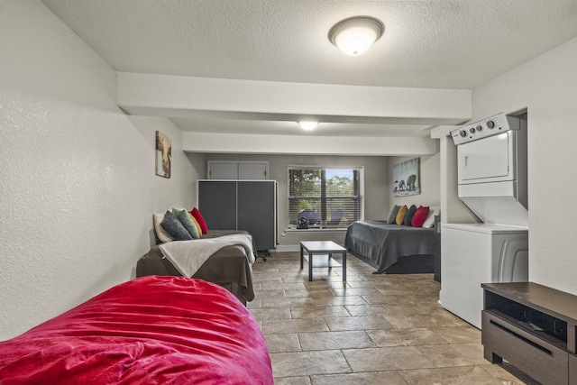 bedroom featuring stacked washer and dryer and a textured ceiling