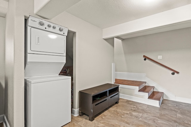 clothes washing area with a textured ceiling, stacked washer and clothes dryer, and light tile patterned floors