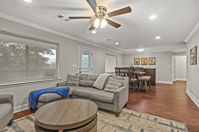 living room featuring ceiling fan, ornamental molding, and dark hardwood / wood-style flooring