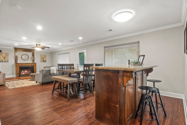 bar with light stone counters, dark hardwood / wood-style floors, ceiling fan, and ornamental molding