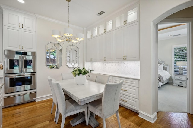 dining room featuring crown molding, hardwood / wood-style floors, and a notable chandelier