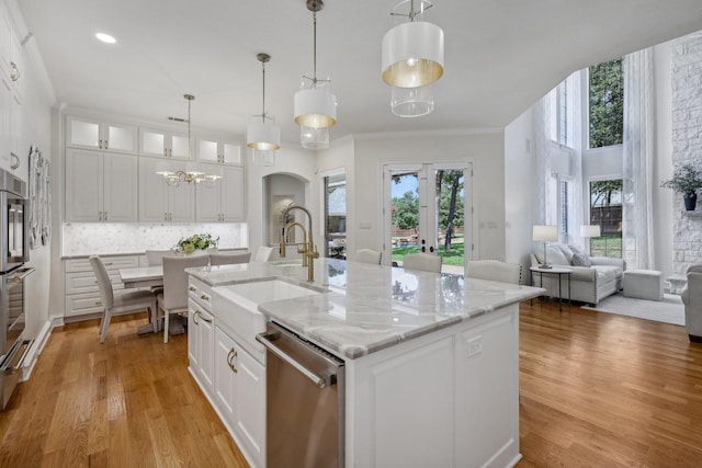 kitchen featuring white cabinetry, dishwasher, sink, and an island with sink