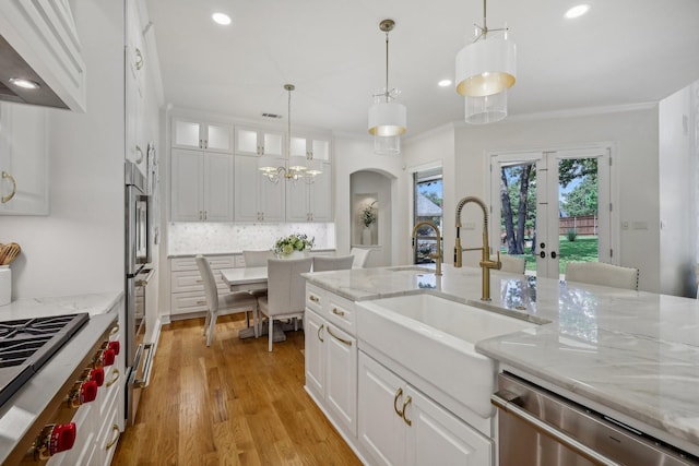 kitchen with sink, tasteful backsplash, hanging light fixtures, stainless steel appliances, and white cabinets