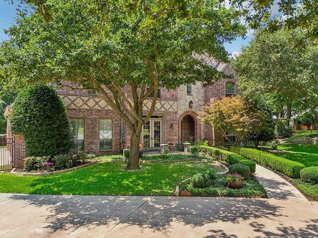 tudor home with french doors and a front yard