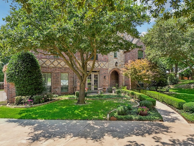 tudor home with french doors and a front yard