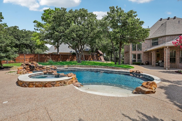 view of swimming pool featuring a playground, an in ground hot tub, and a patio area