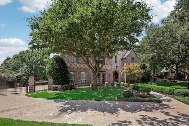 tudor-style house with french doors and a front yard