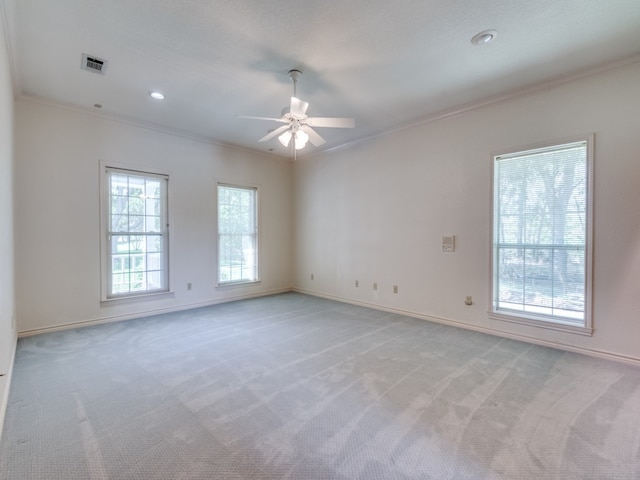 empty room with light carpet, a ceiling fan, crown molding, and baseboards